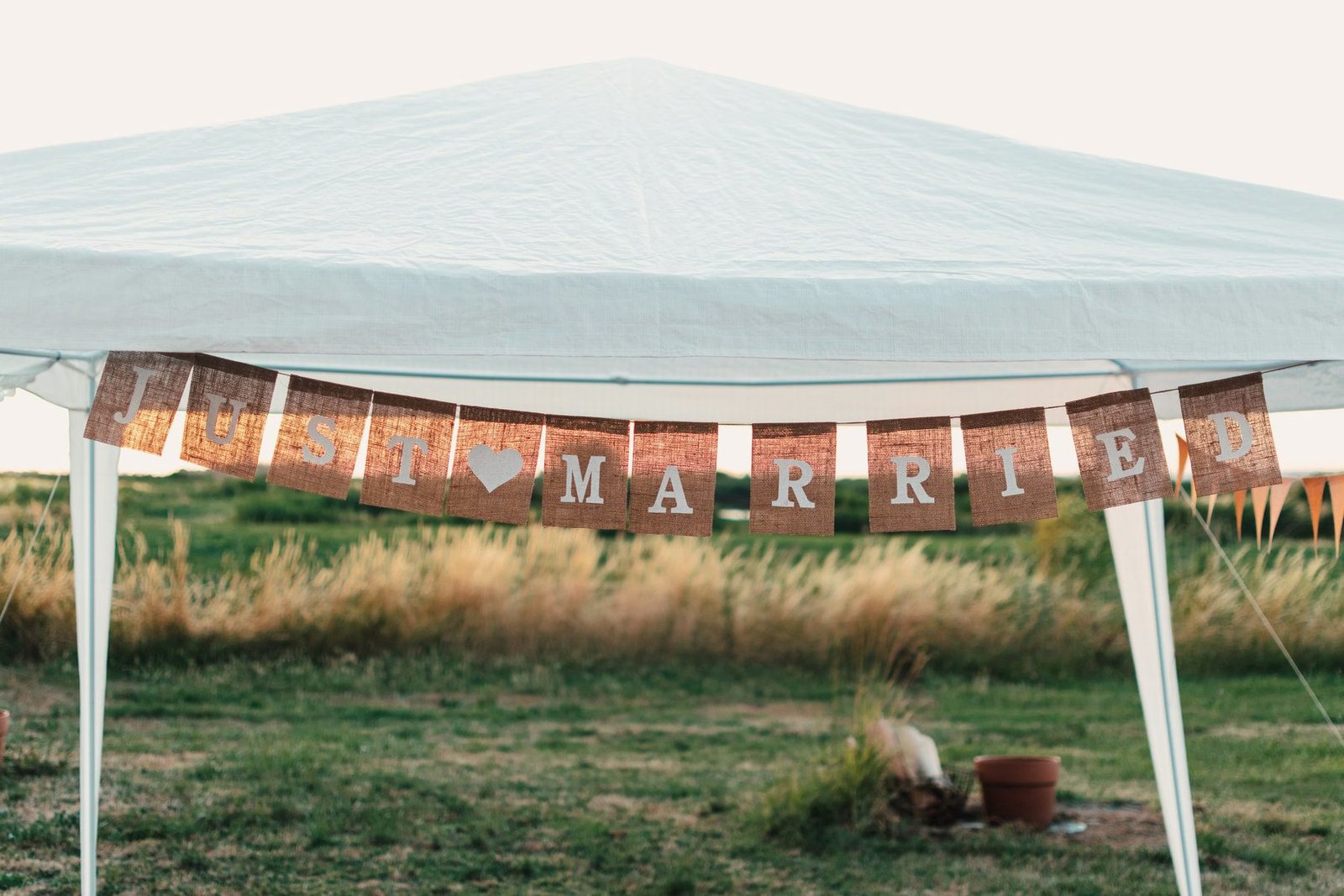 Rustic wedding banner strung between posts at an outdoor venue.