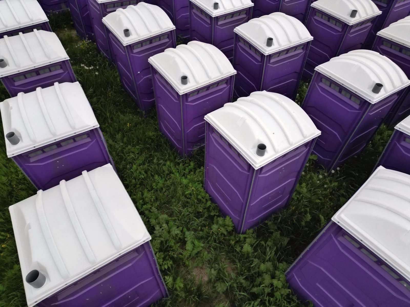 Overhead view of portable restroom units lined up in rows in a yard.